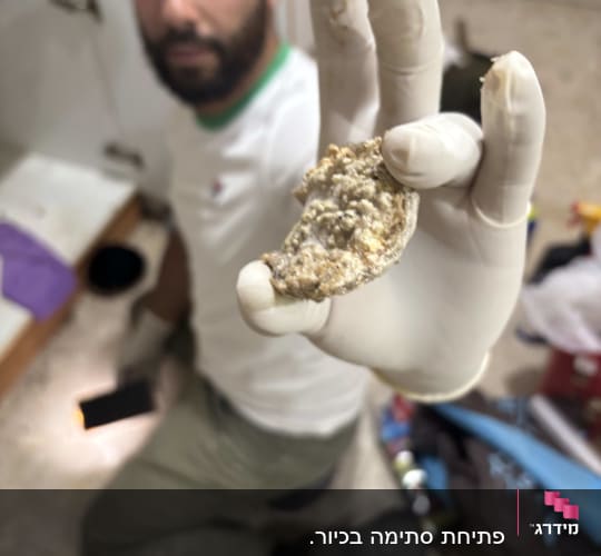 אדם עם כפפות מחזיק גוש סתימה בצנרת